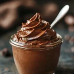 Close-up of a creamy no-bake chocolate pudding cup in a glass jar with a swirl on top, natural light