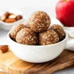Bowl of healthy no-bake apple pie energy balls with oats, apples, and cinnamon on a wooden board